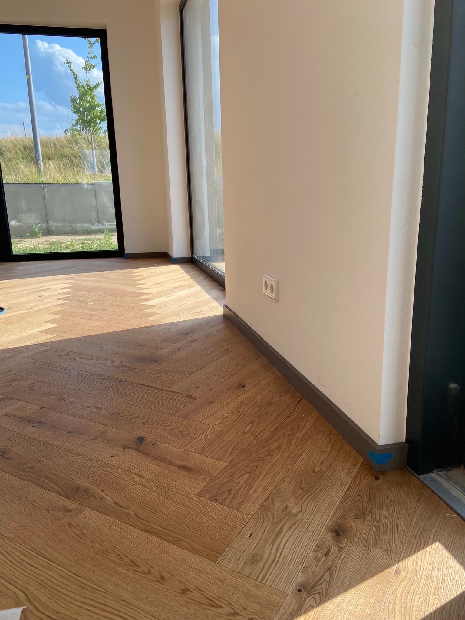 Ein Wohnzimmer mit einem Holzboden und einem großen Fenster