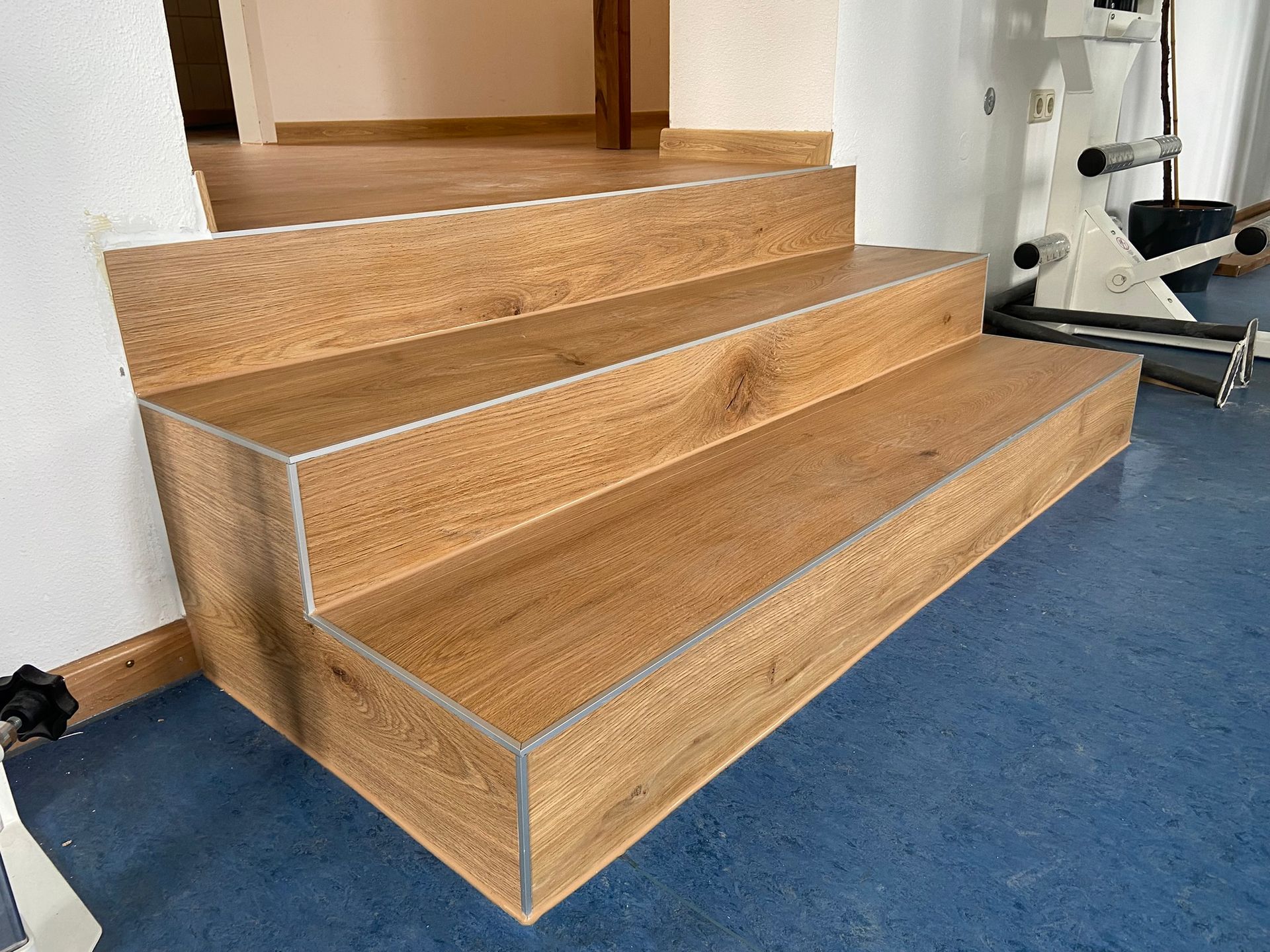 Eine Holztreppe führt in ein Fitnessstudio