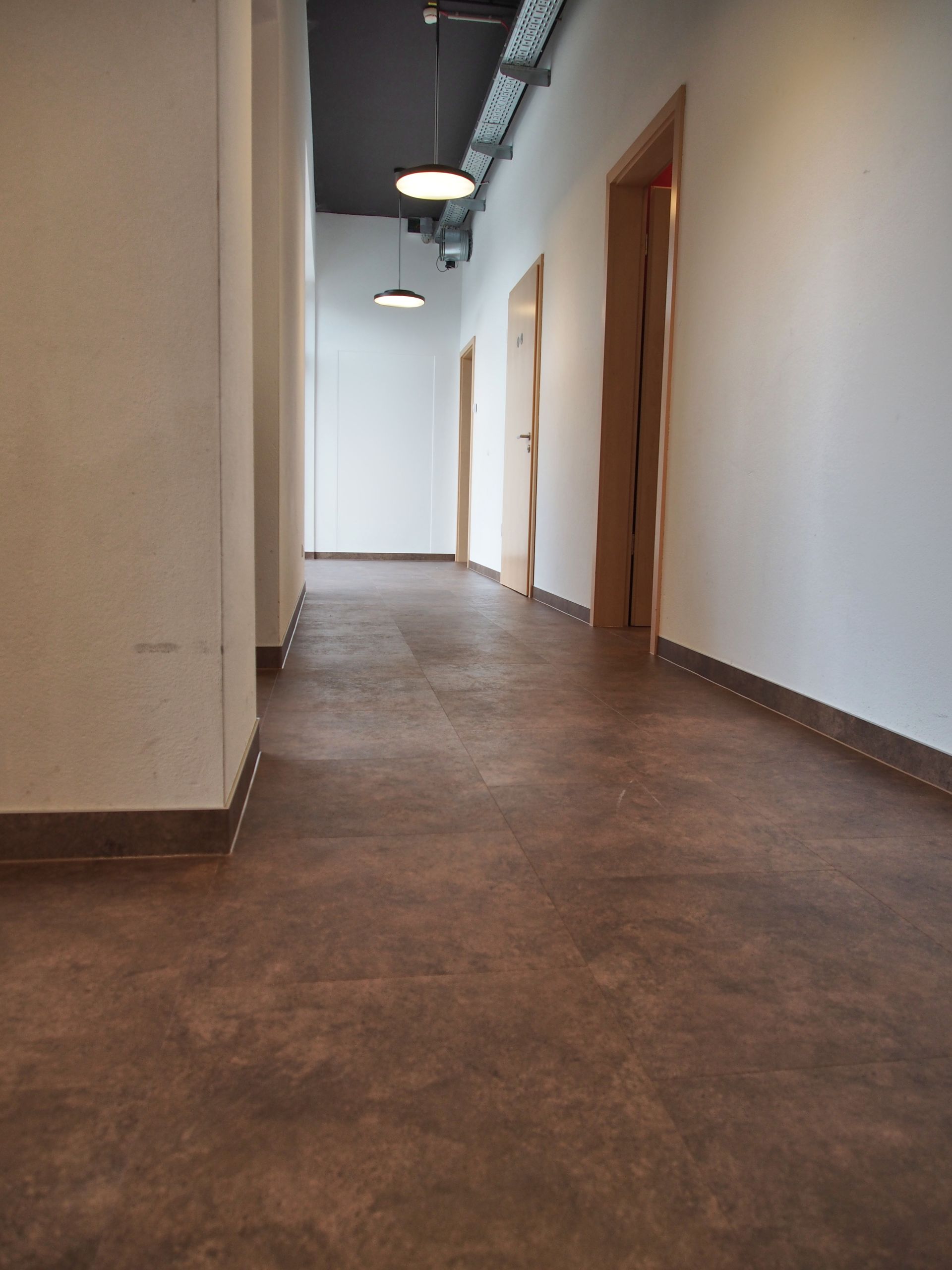 Ein Flur mit braunem Boden und weißen Wänden