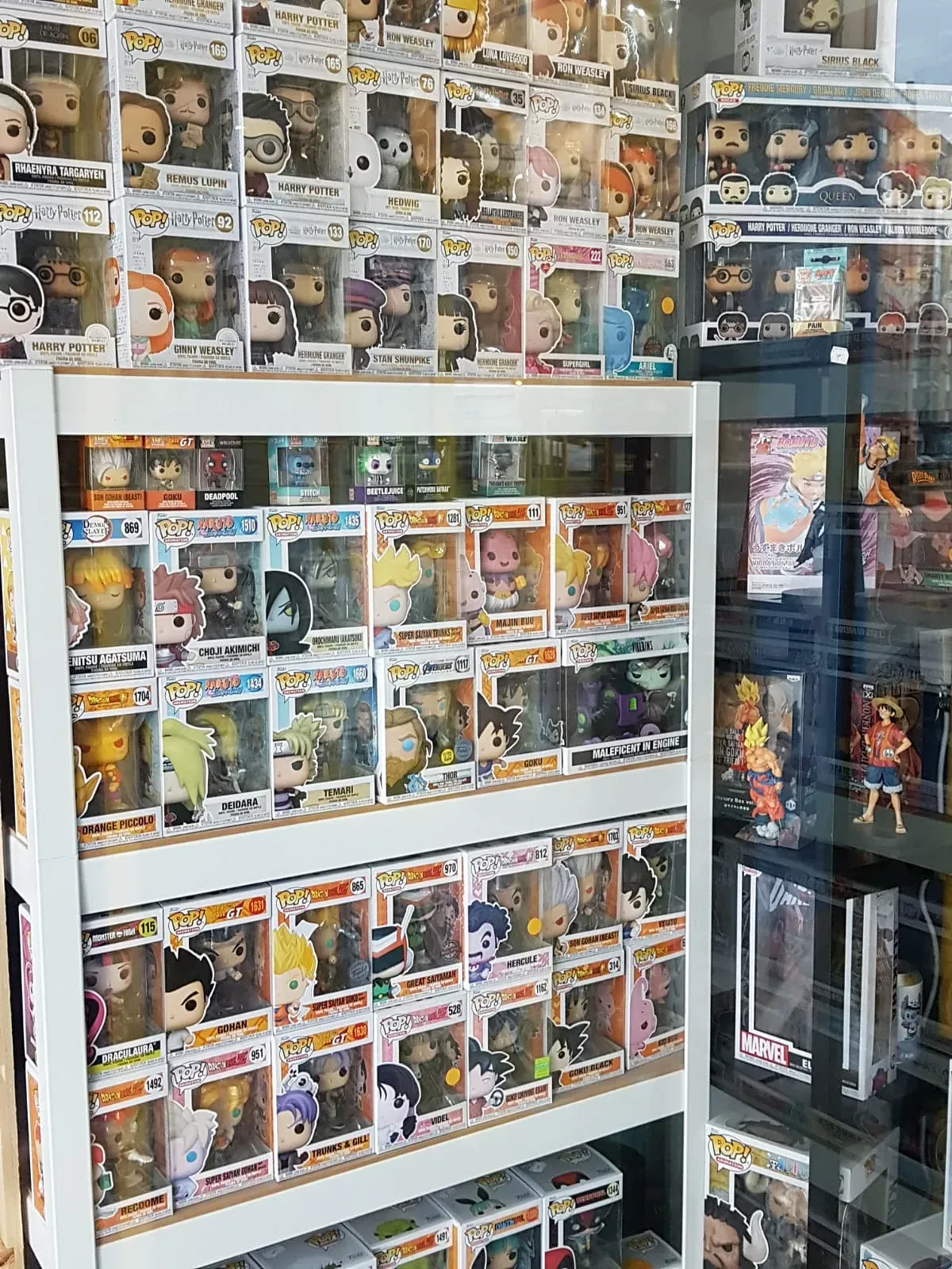 Un escaparate de una tienda muestra muchas figuras Funko Pop en cajas, en estantes y apiladas contra una pared, con algunos temas de anime.