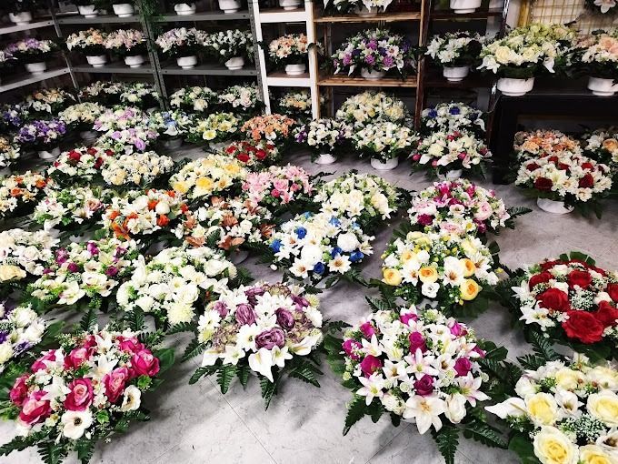 Numerosos arreglos florales coloridos en exhibición en una floristería. Muchas flores blancas y de diversos colores adornan los ramos.