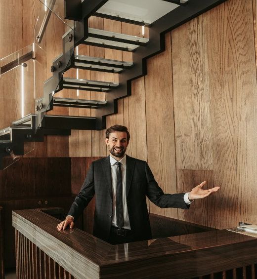 Un hombre con traje y corbata está parado frente a una escalera de madera.