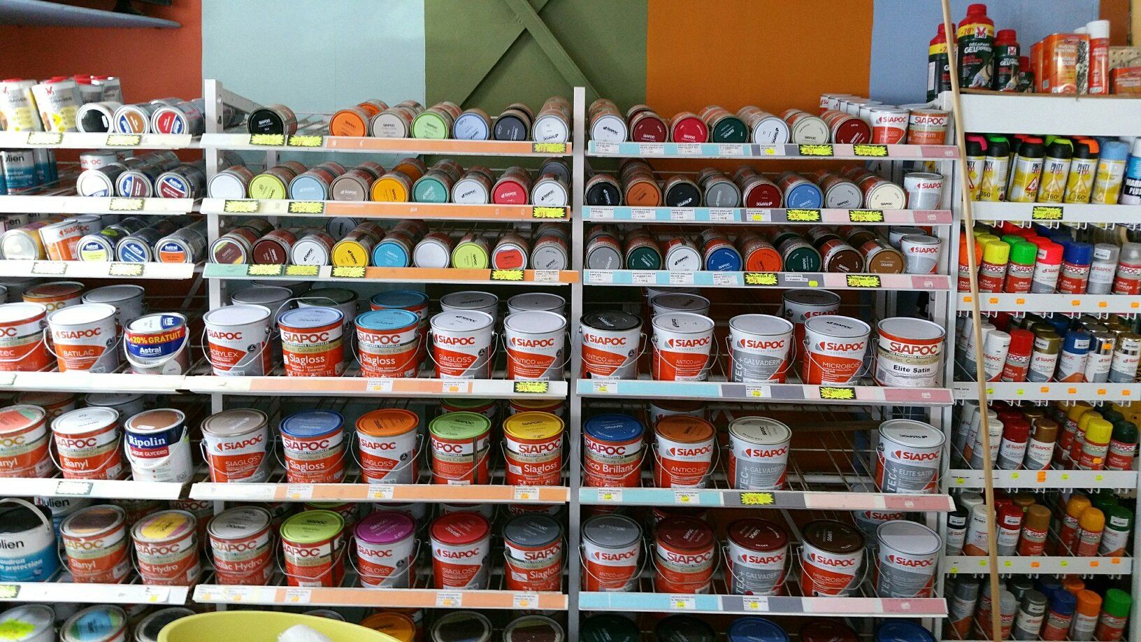 Des étagères de pots de peinture de différentes couleurs dans une quincaillerie.