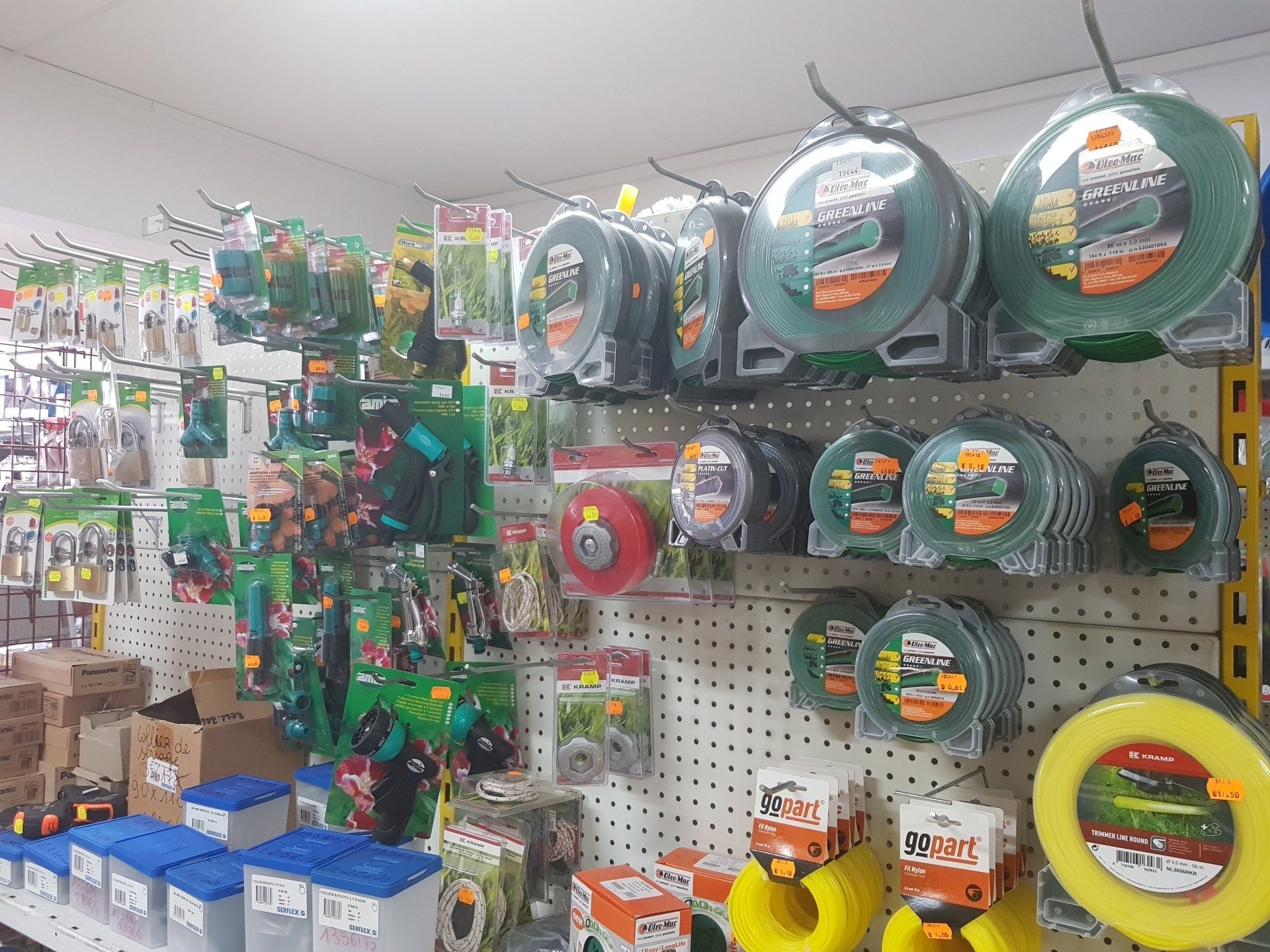 Présentoir de quincaillerie présentant du fil de coupe-bordures et des outils de jardinage.