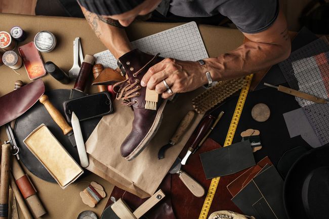 Gros plan sur plusieurs bottes en cuir marron alignées, avec un focus sur le détail du laçage de la paire de devant.