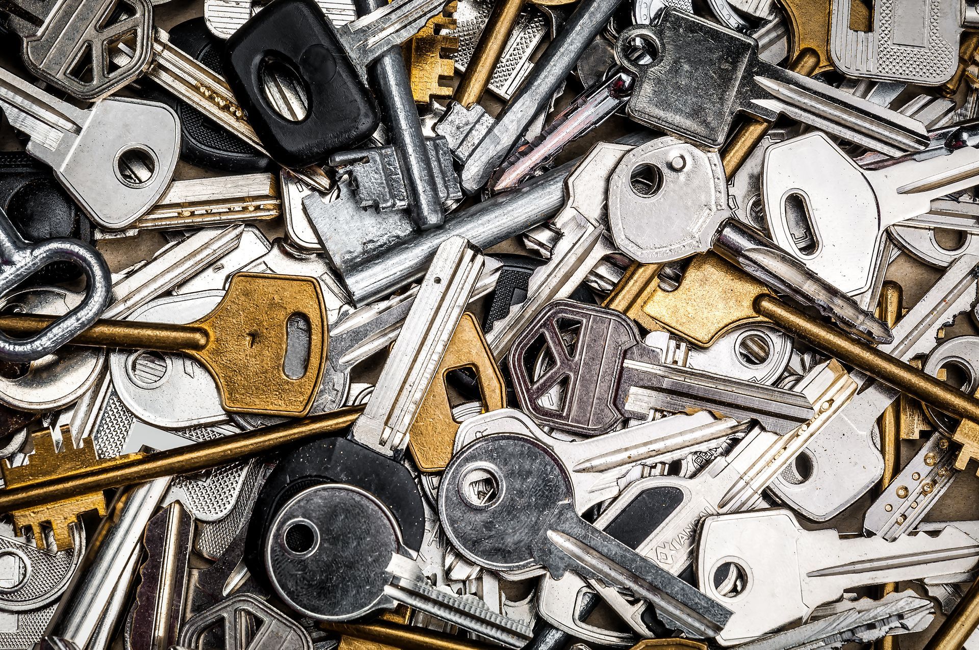 Un amas chaotique de clés métalliques de couleurs argentée, dorée et noire, se chevauchant sur une surface plane.