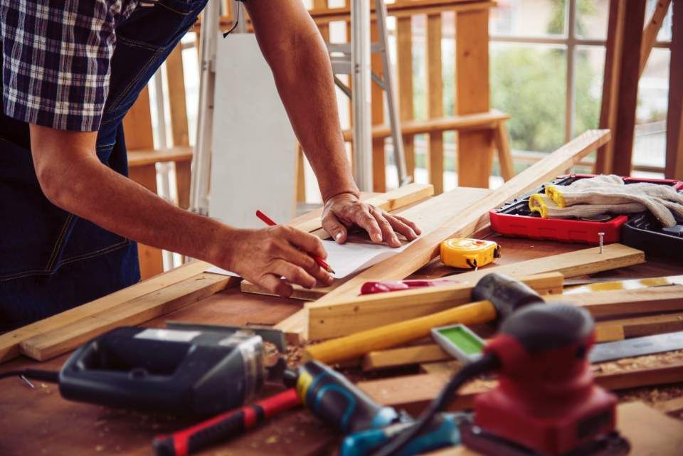 Ein Mann bearbeitet in einer Werkstatt ein Stück Holz.