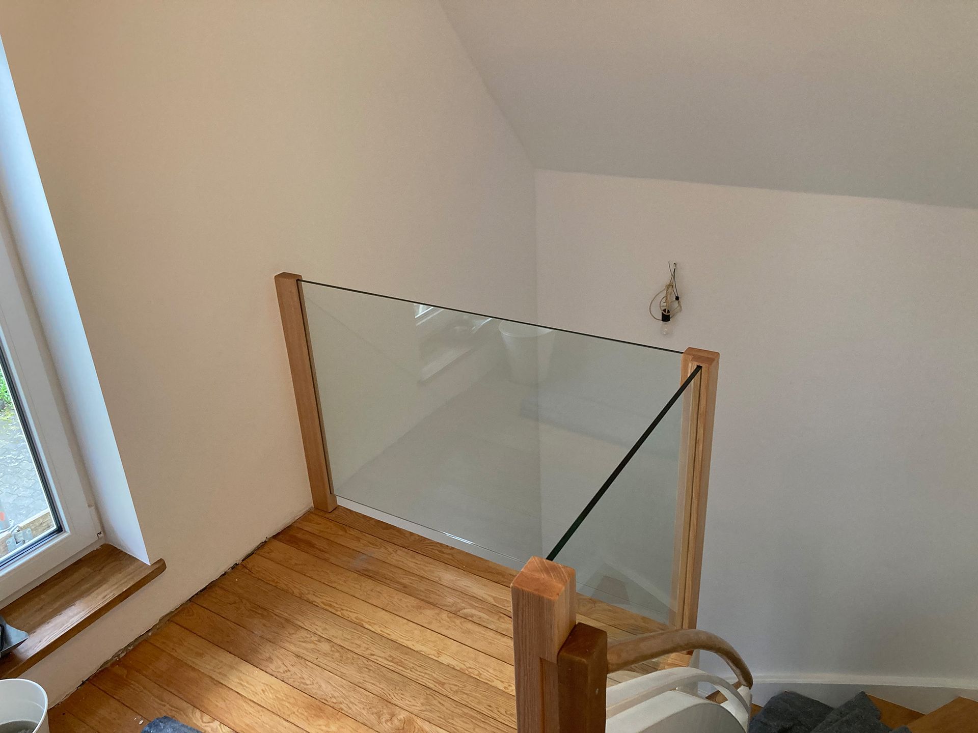 Eine Holztreppe mit Glasgeländer und Fenster.