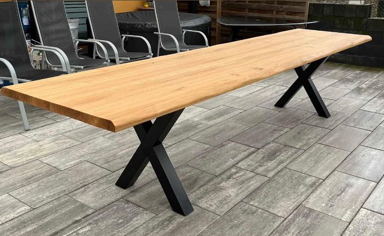 Ein Holztisch mit schwarzem Metallrahmen steht auf einem gefliesten Boden.