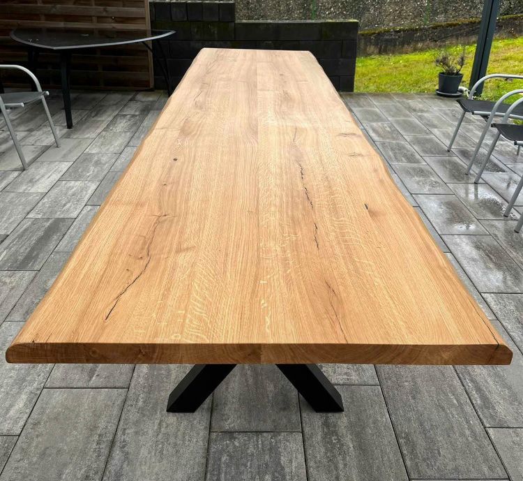 Ein langer Holztisch steht auf einer gefliesten Terrasse