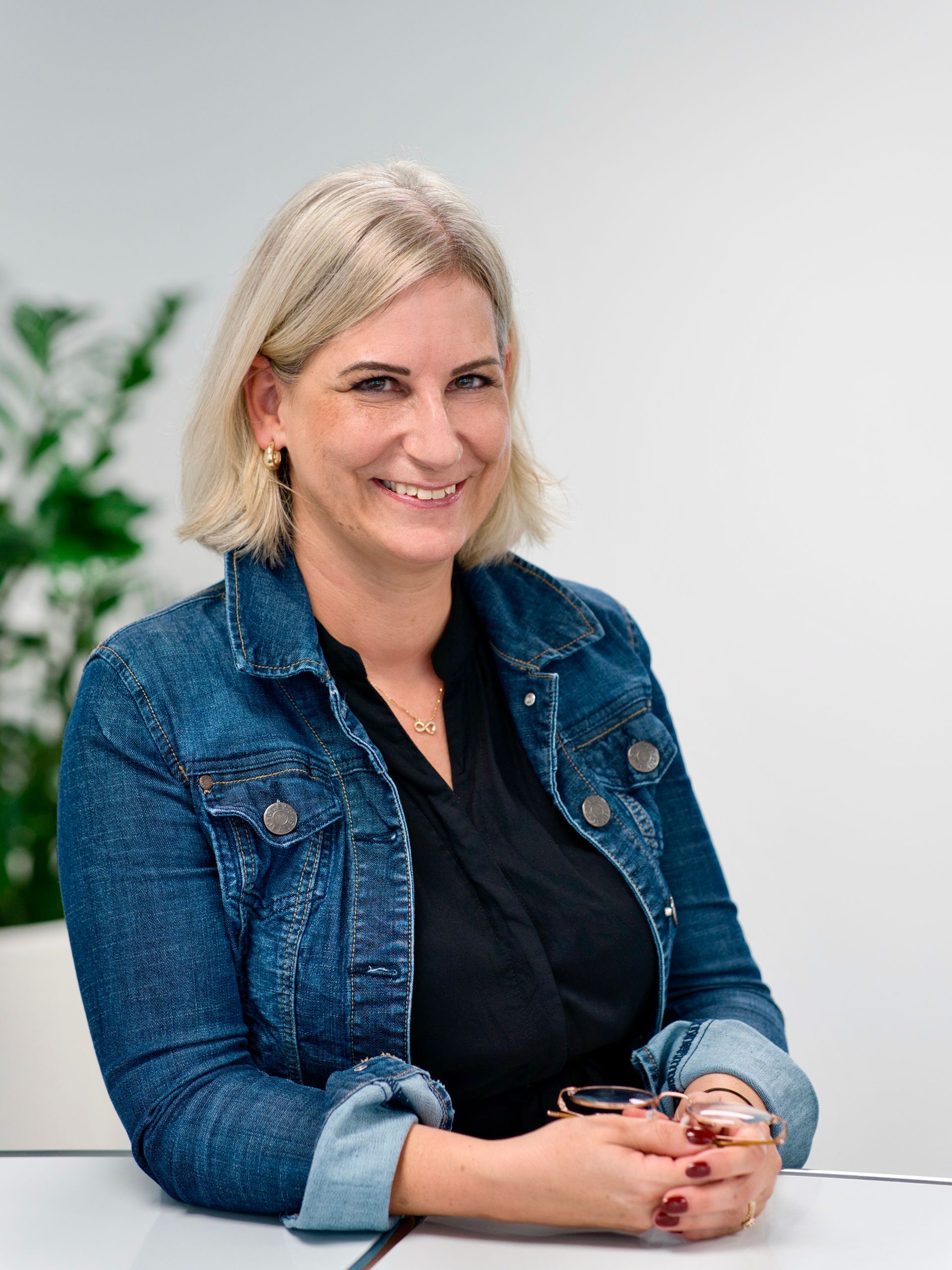 Eine Frau in einer schwarzen Jacke lächelt in die Kamera.