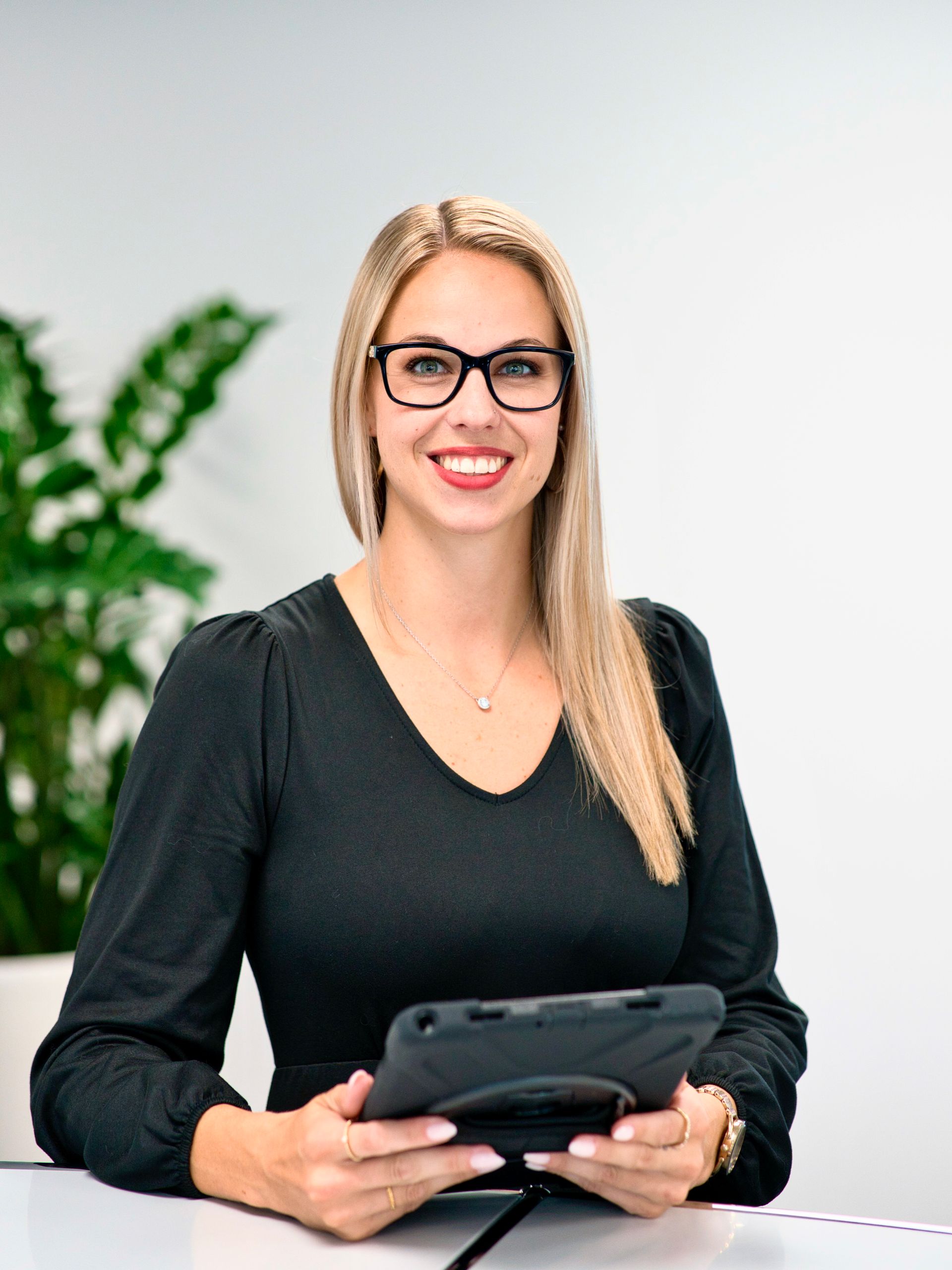 Eine Frau mit Brille und weißem Hemd lächelt in die Kamera.