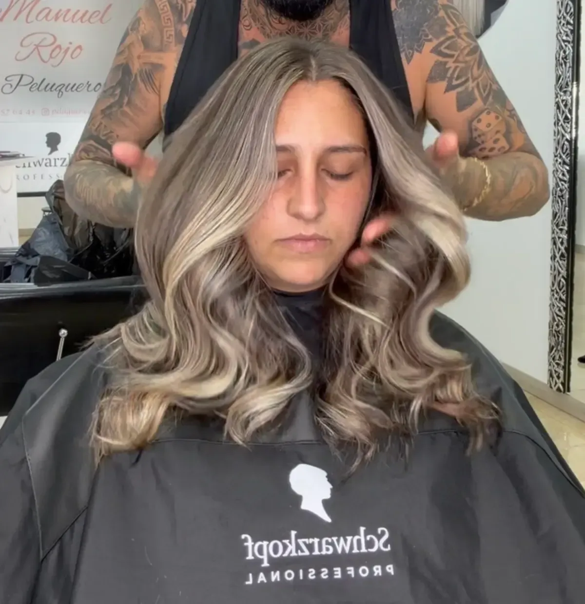Una persona se está haciendo un corte de pelo ondulado rubio plateado en una peluquería
