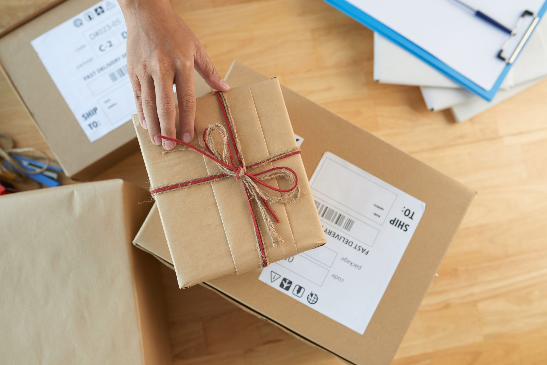 Déposer à la main un cadeau emballé sur un colis en carton avec des étiquettes d'expédition, sur un bureau.