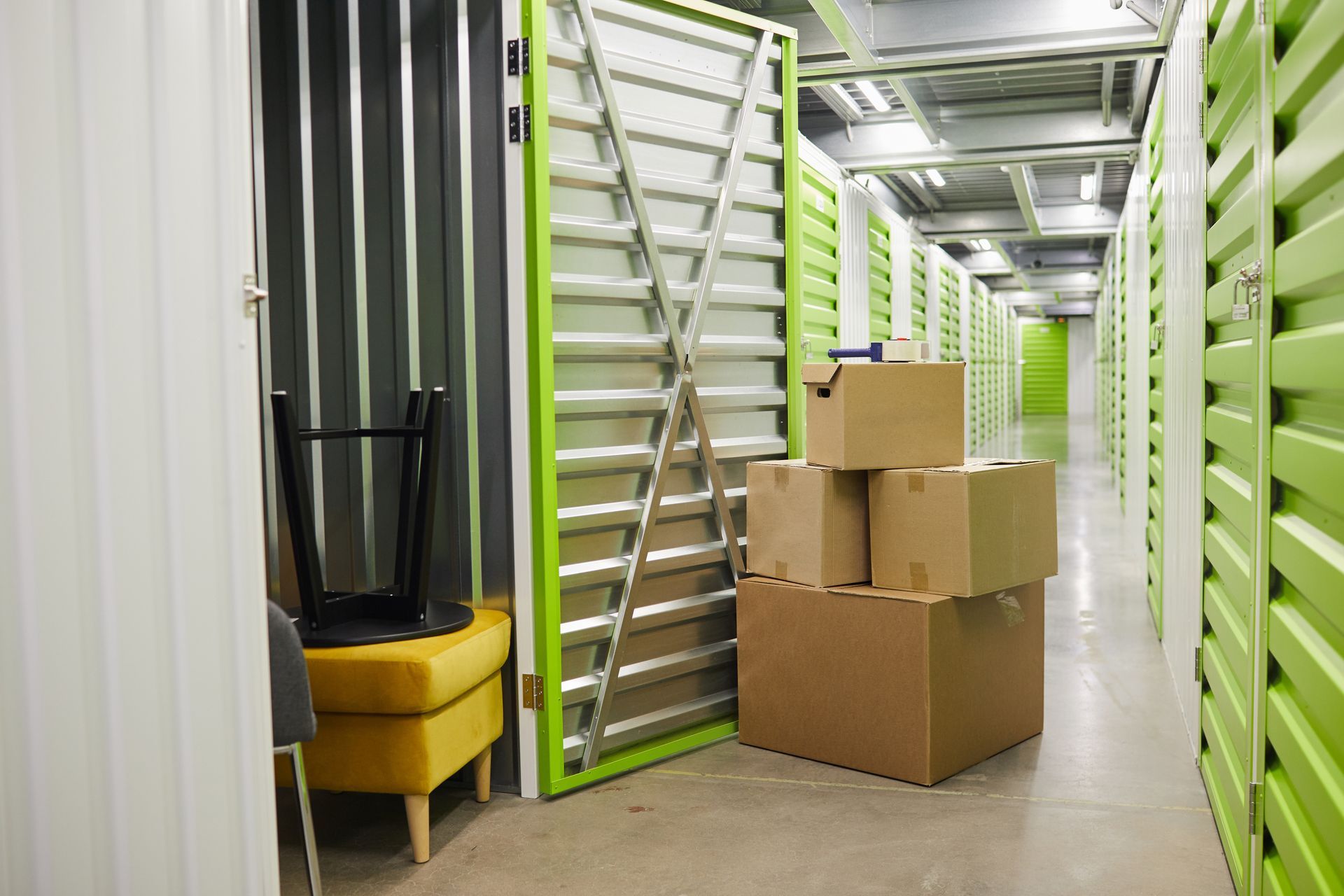 Allée d'un entrepôt avec des cartons empilés et des portes sectionnelles.
