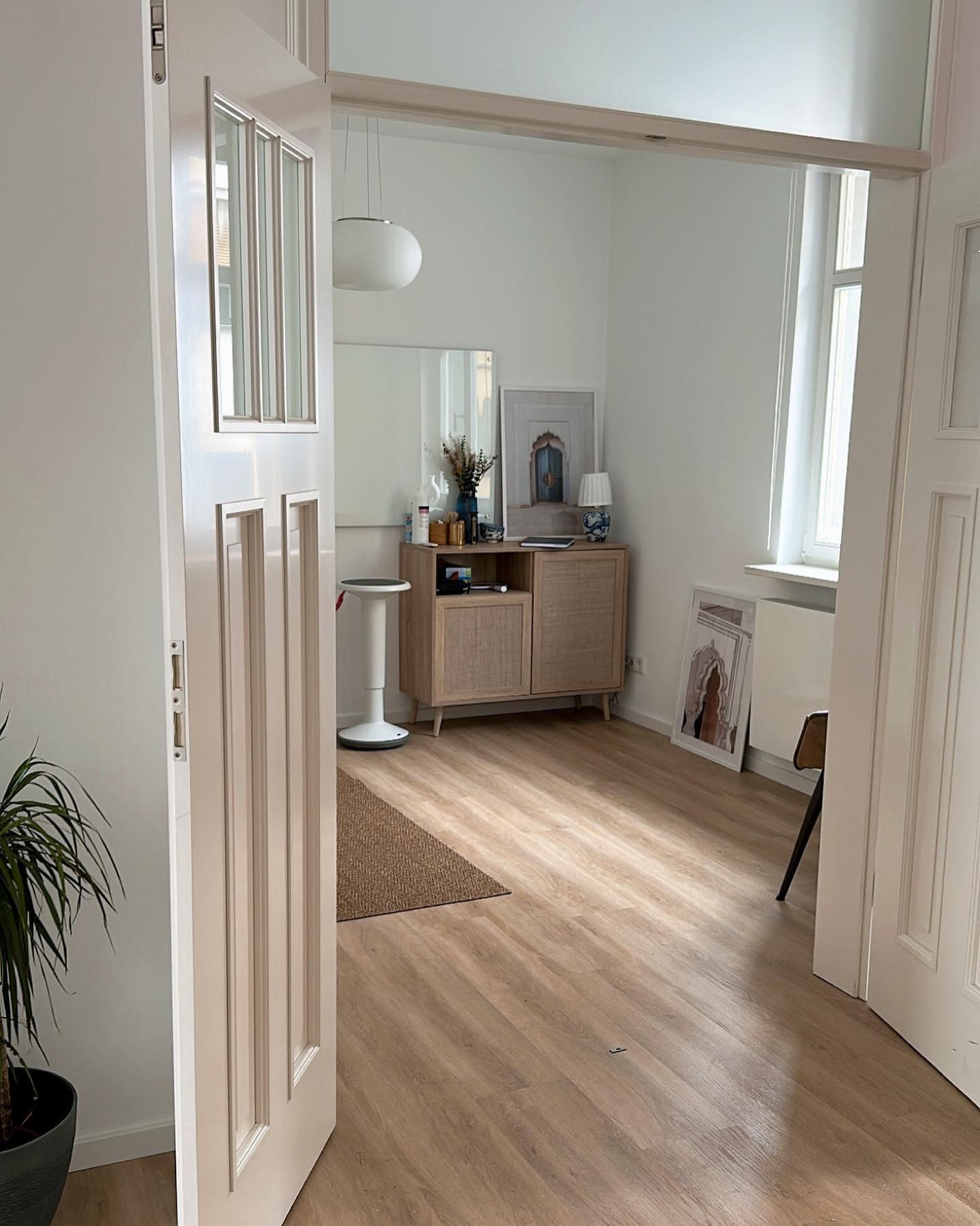 Eine weiße Tür führt zu einem Wohnzimmer mit Holzboden.
