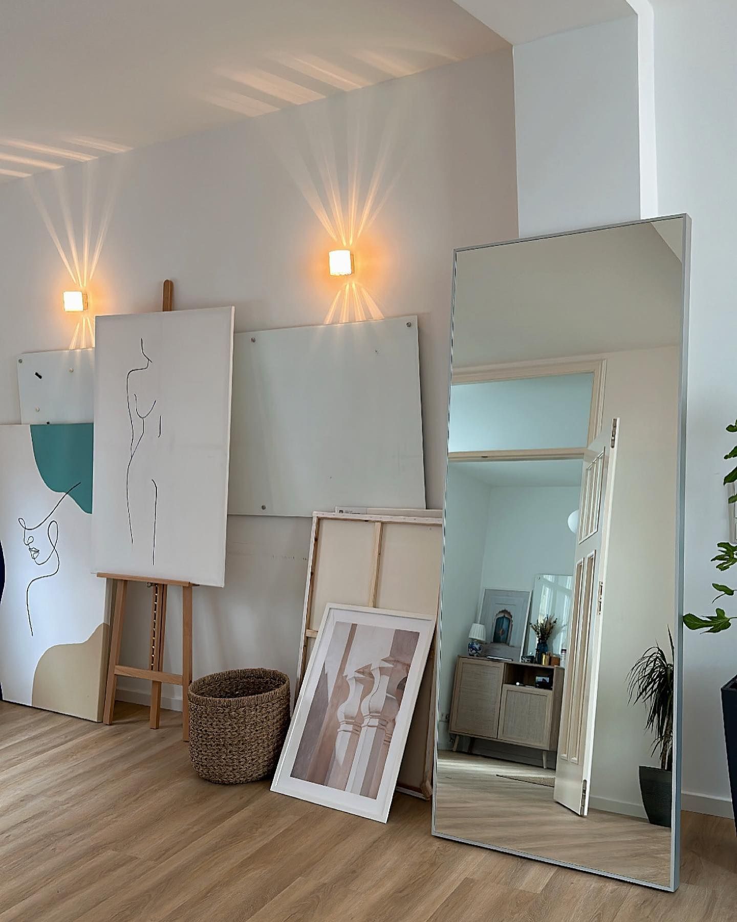 ein großer Spiegel steht in einem Wohnzimmer neben zwei Gemälden
