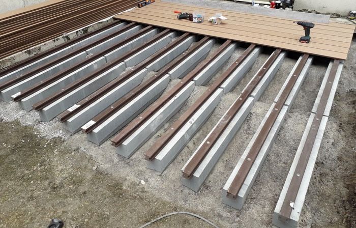 Des panneaux de toiture métalliques disposés au sol, à côté de planches de bois empilées