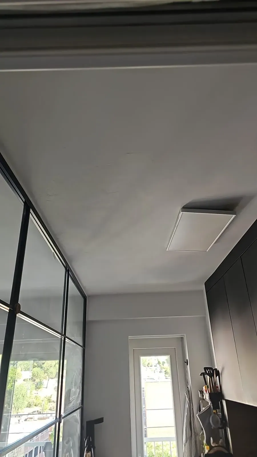 Pasillo interior moderno con paredes grises, techo alto, puerta con ventana y perchero junto a la entrada.