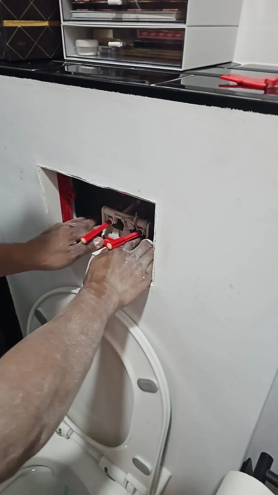 Manos que utilizan herramientas rojas para reparar una abertura