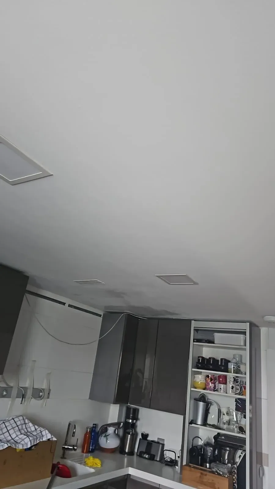 Cocina pequeña con techo inclinado, encimeras, electrodomésticos y una despensa abierta.