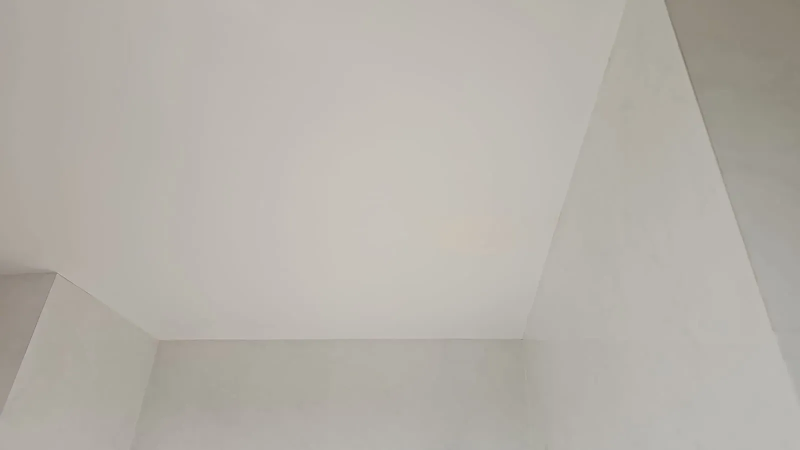 Techo interior blanco con paredes inclinadas y una esquina empotrada.