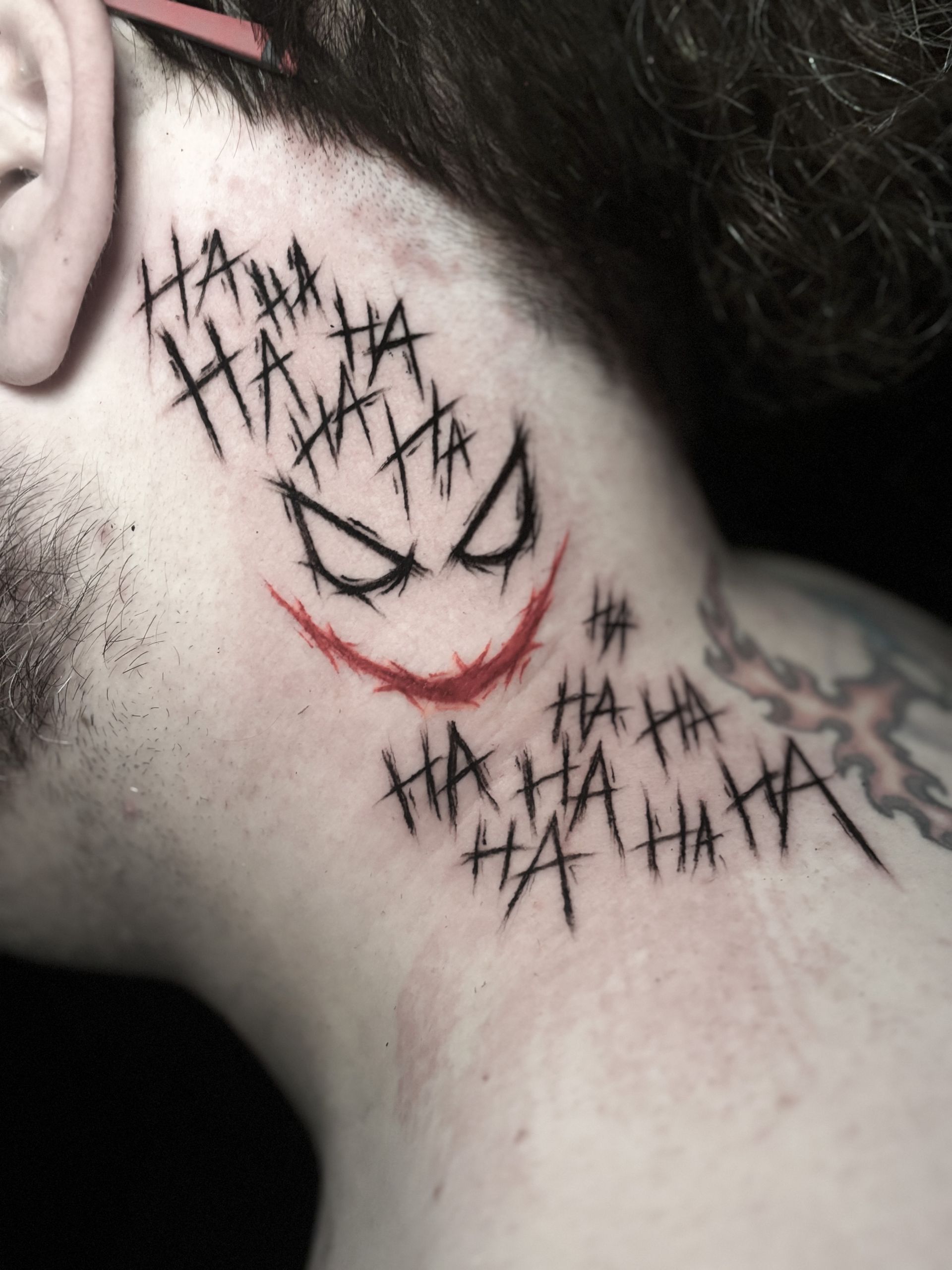 Tatuaje de la cara del Joker y el texto 