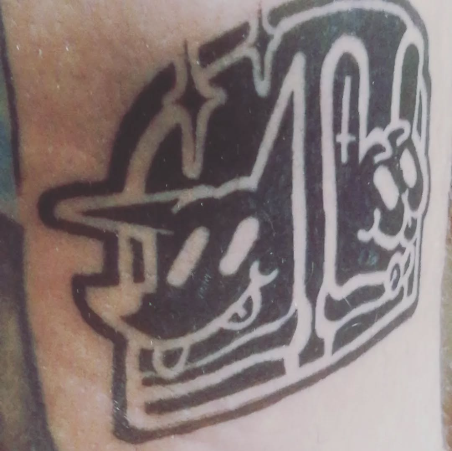 Tatuaje negro de un perro de dibujos animados que lleva gafas de sol junto a un conejo que sostiene el signo de la paz.