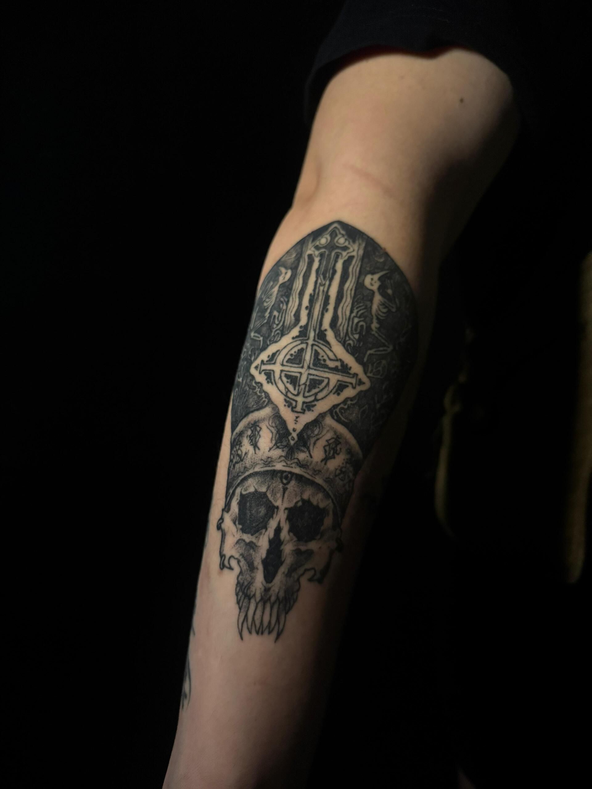 Tatuaje de una calavera con corona y un tocado gótico en el brazo de una persona.