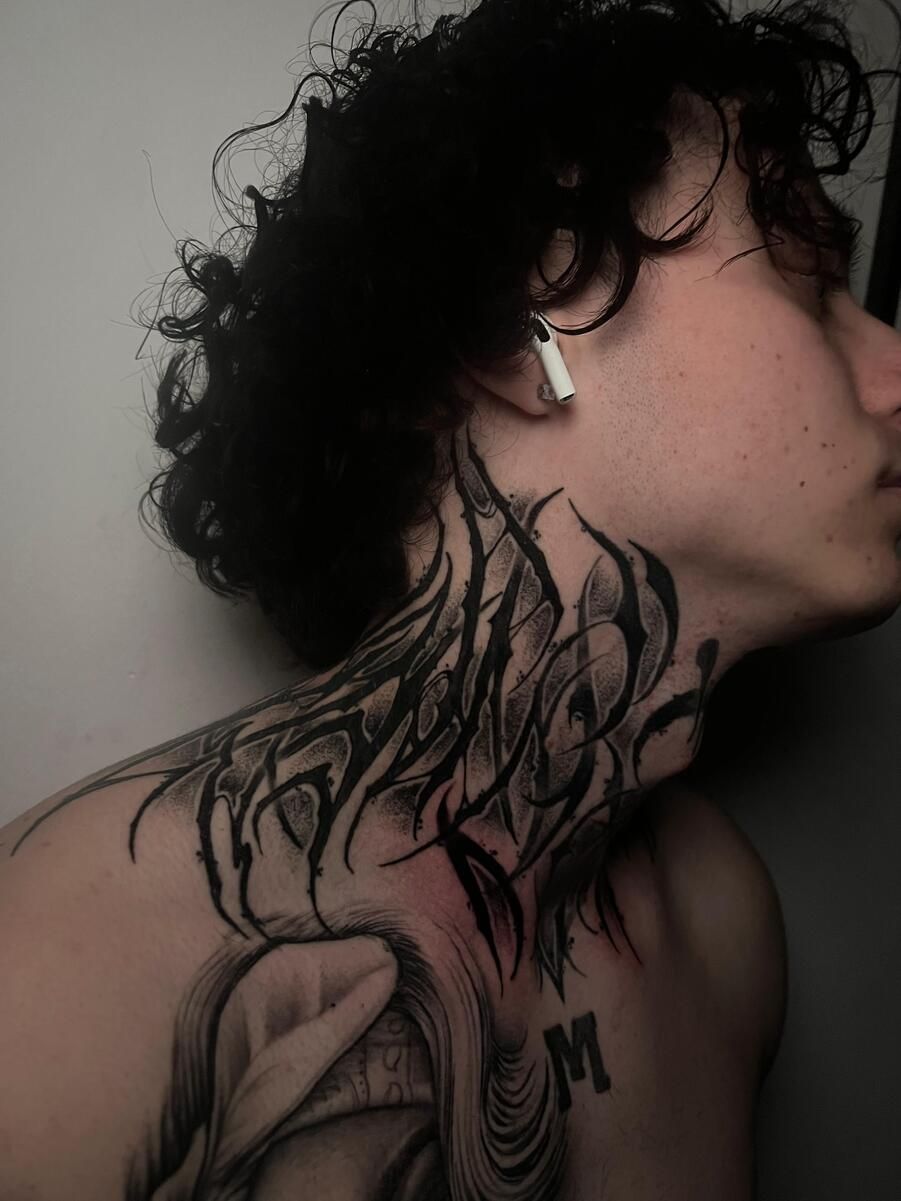 Hombre con cabello rizado y tatuaje en el cuello, usando un auricular.
