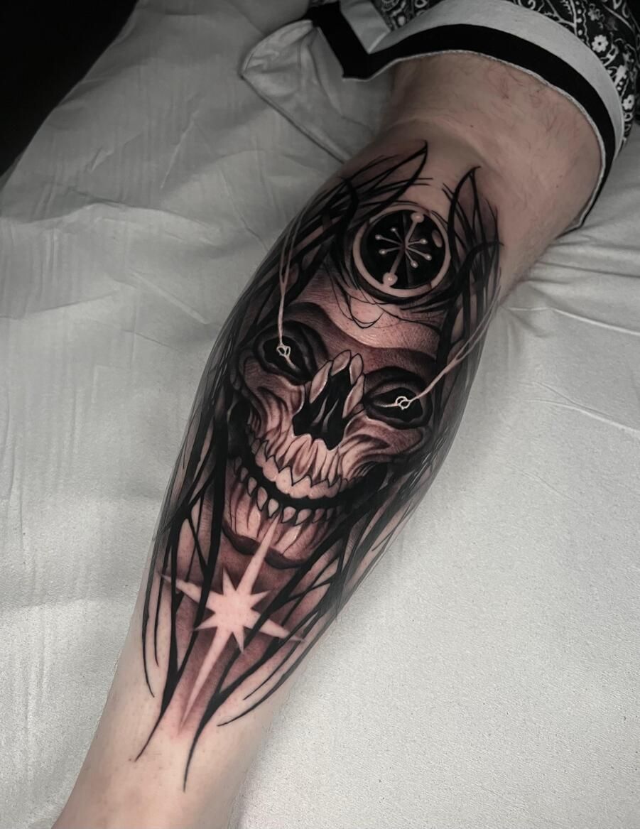 Tatuaje de calavera en la pierna. Sombreado en negro y gris con una estrella en la parte inferior.