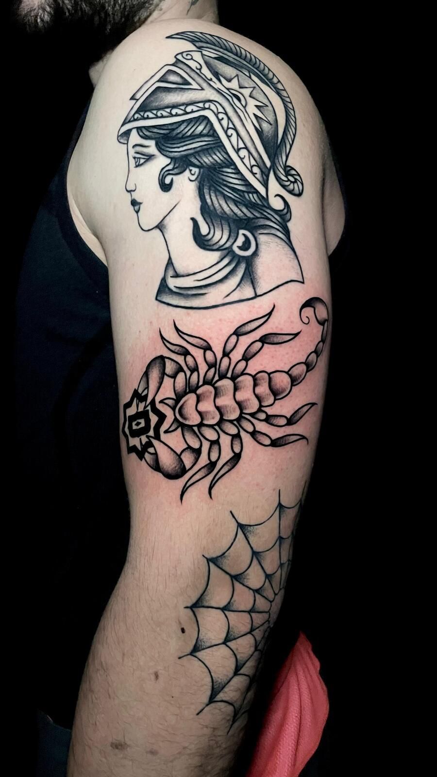 Tatuajes en el brazo en blanco y negro: mujer con casco, escorpión y telaraña.