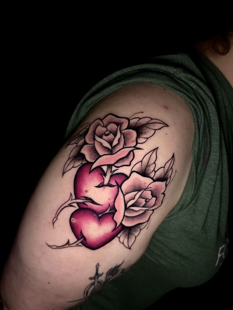 Tatuaje de dos corazones entrelazados con rosas en el brazo. Corazones rosa oscuro, rosas rosa pálido y camisa verde.