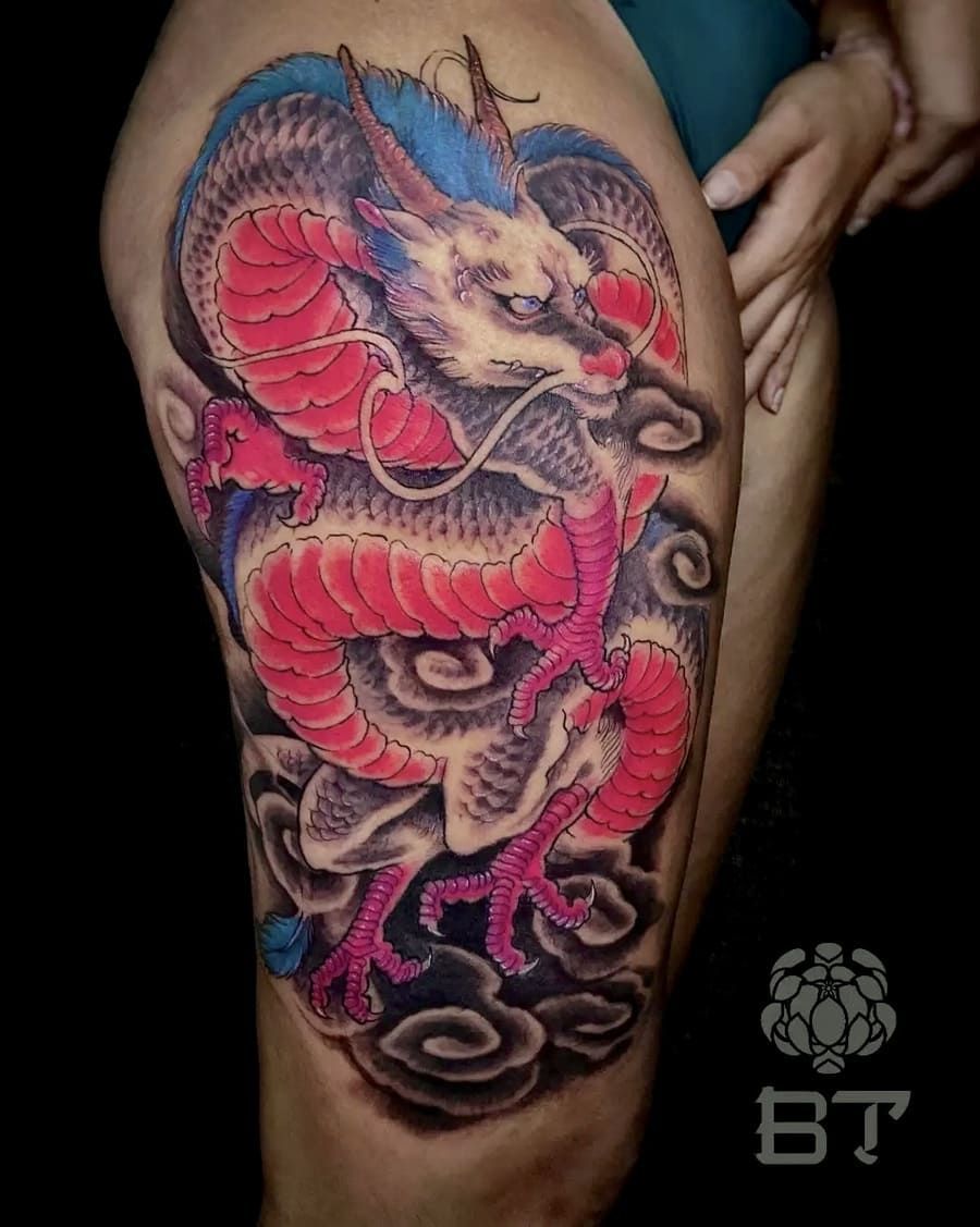 Tatuaje de dragón colorido en el muslo de una persona, rodeado de nubes oscuras.