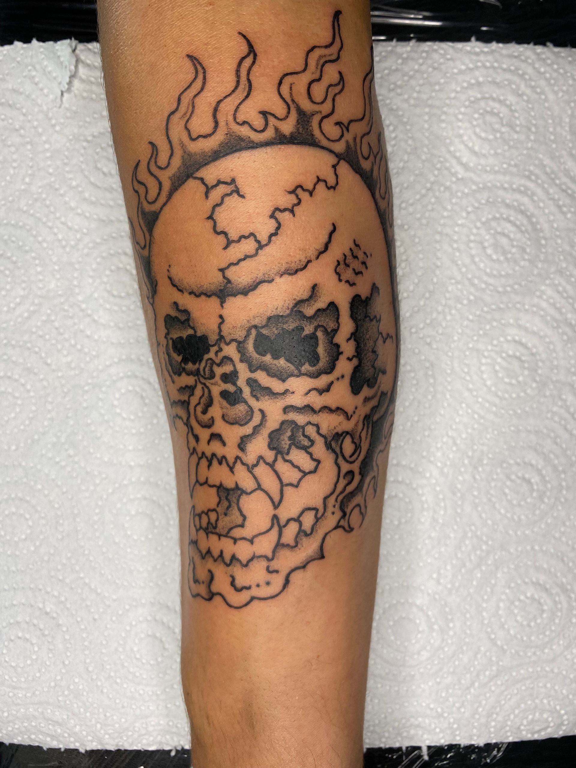 Tatuaje de calavera con llamas en el antebrazo.
