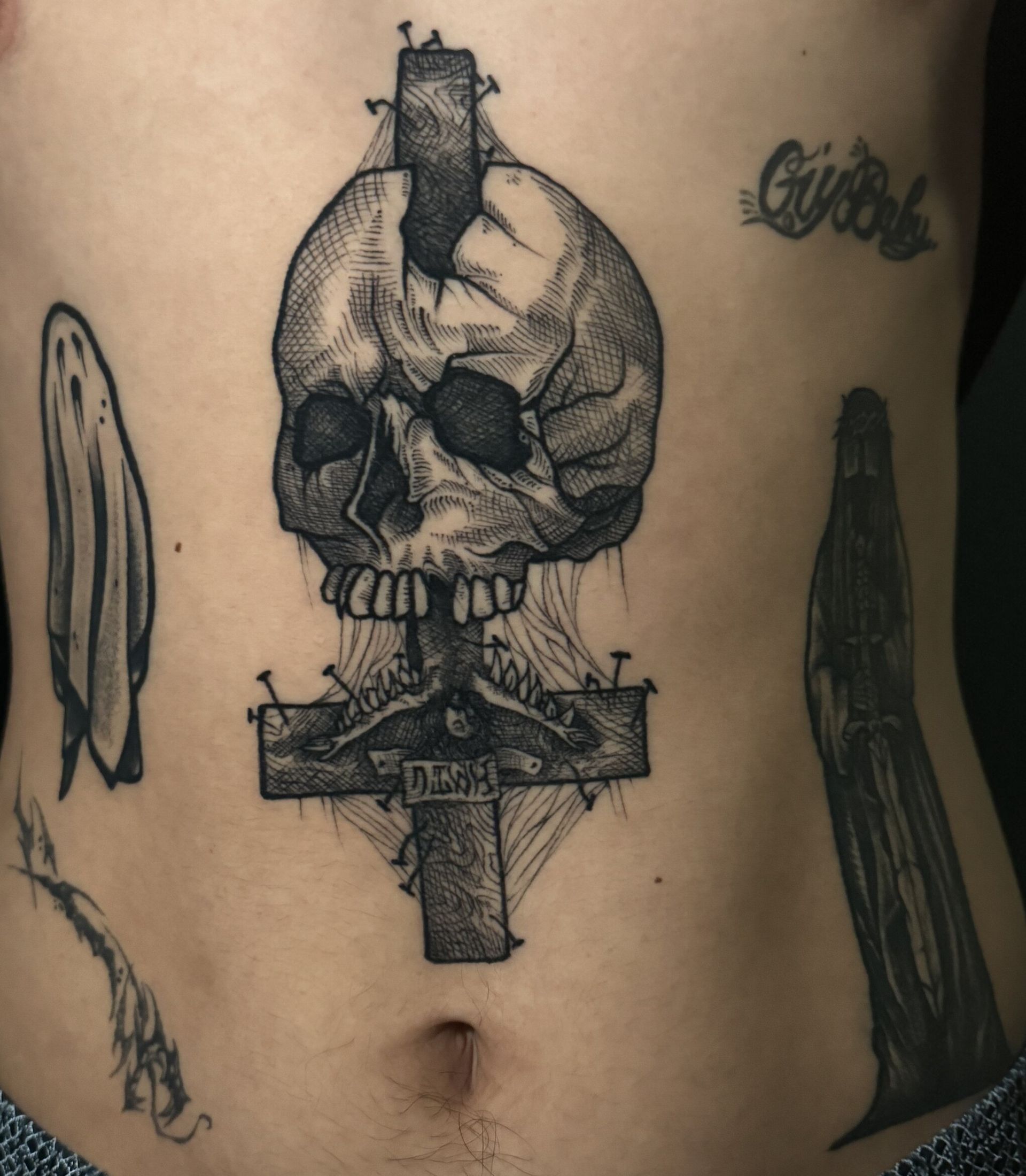 Tatuajes en el torso: calavera en cruz invertida, fantasma, parca, letra cursiva 