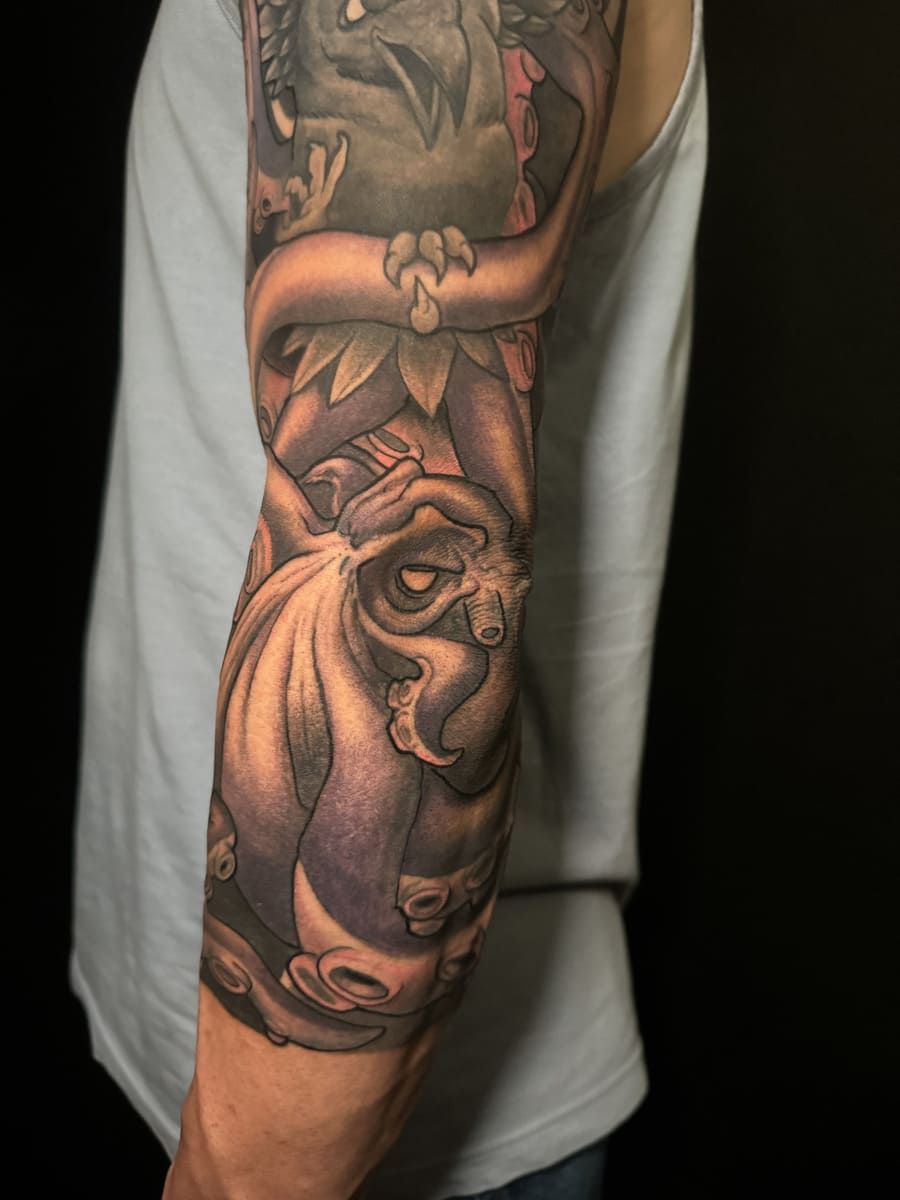 Tatuaje de un pulpo gris estilizado envuelto alrededor de un brazo.