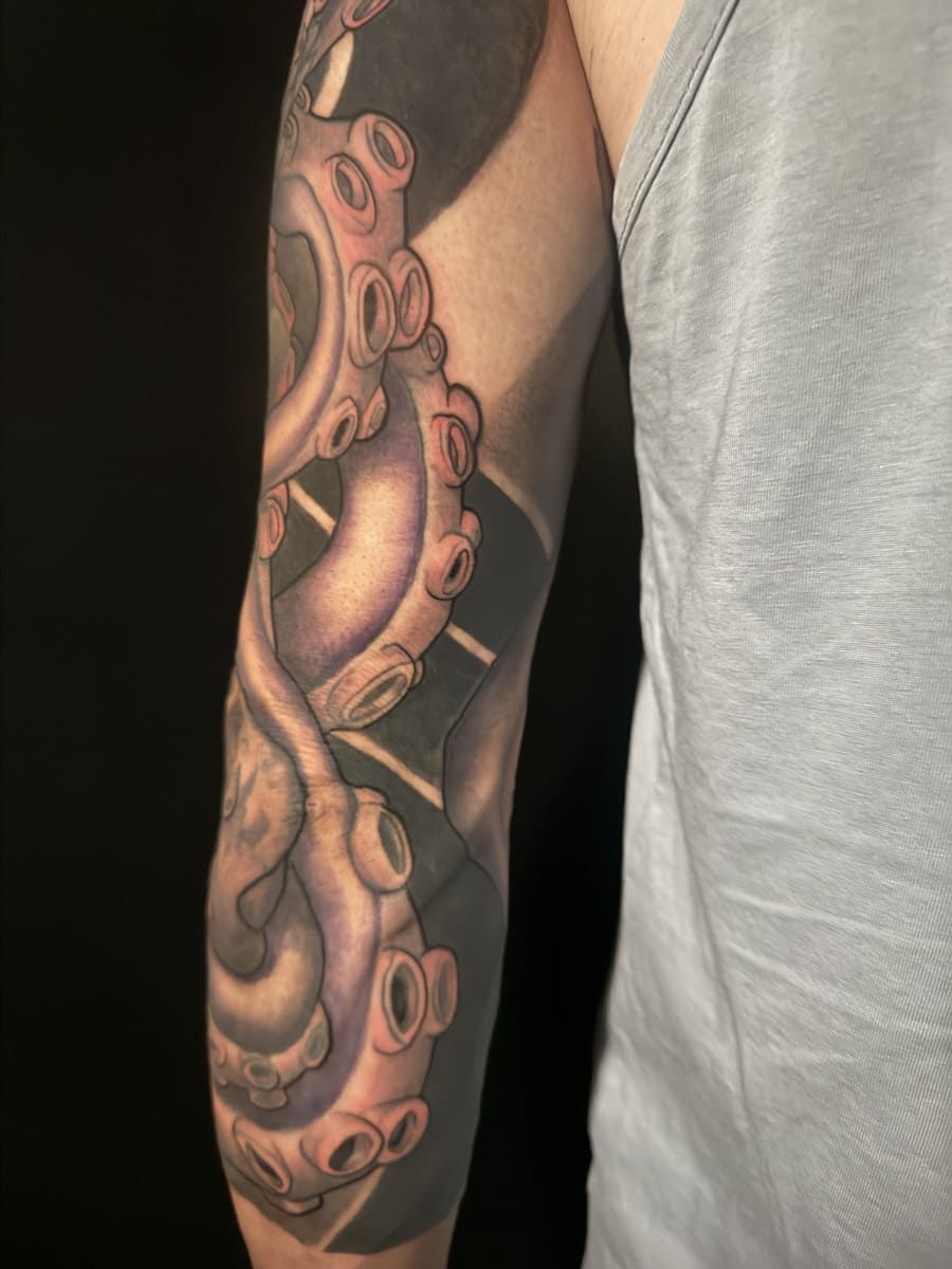 Tatuaje en el brazo de un tentáculo de pulpo estilizado en blanco y negro con sombreado gris.