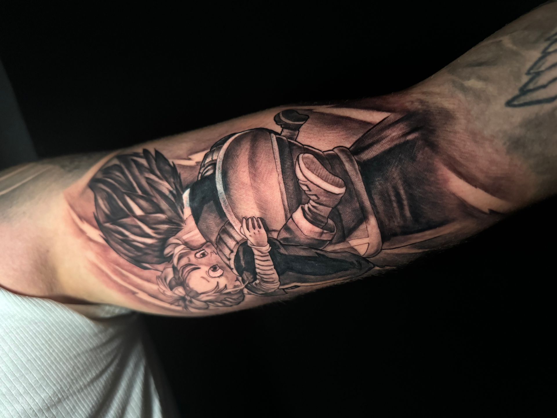Tatuaje en blanco y negro en el brazo que representa a una persona con un casco redondo, mirando hacia arriba.