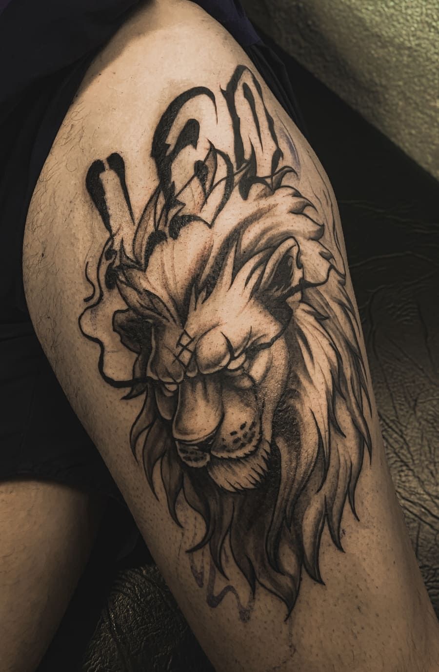 Tatuaje de león en una pierna, sombreado detallado en blanco y negro, melena suelta.