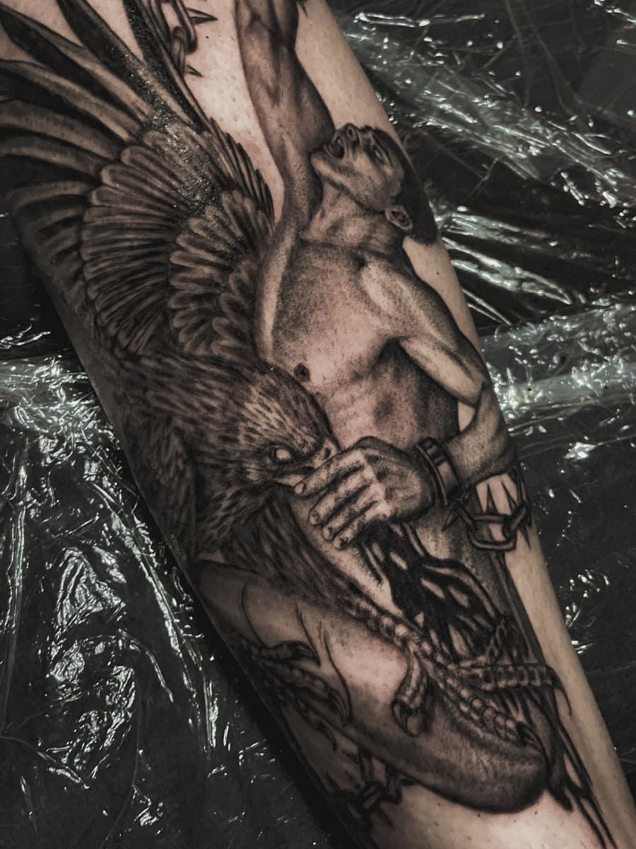 Un tatuaje de un pájaro mítico atacando a una persona atada, en tinta negra y gris.