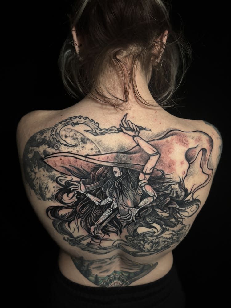 Artista del tatuaje haciendo un tatuaje en el brazo de alguien en un salón de tatuajes con poca luz.