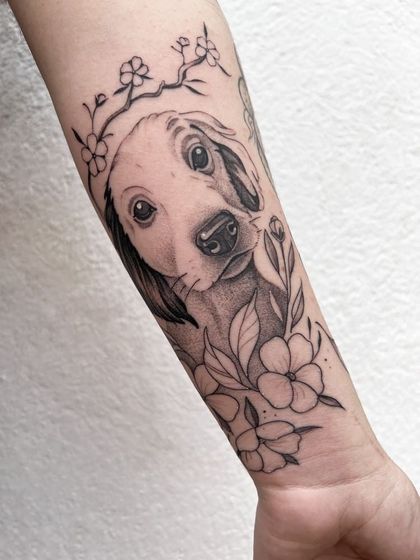 Artista del tatuaje entintando un diseño floral en el brazo de una persona, toma de detalle.