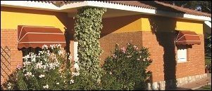 Una casa de ladrillo con un toldo rojo en las ventanas
