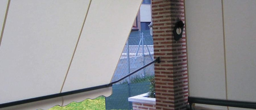 Un balcón con toldo blanco y chimenea de ladrillo.