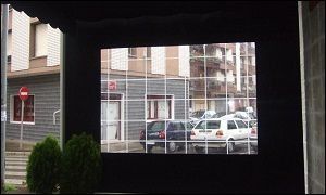 Una pantalla muestra coches aparcados delante de un edificio.