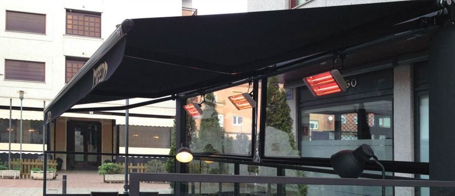 Un restaurante con toldo negro y calentadores en el patio.