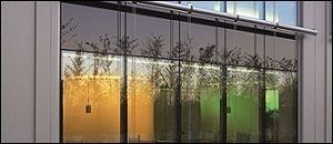 Un edificio con muchas ventanas y árboles reflejados en las ventanas.