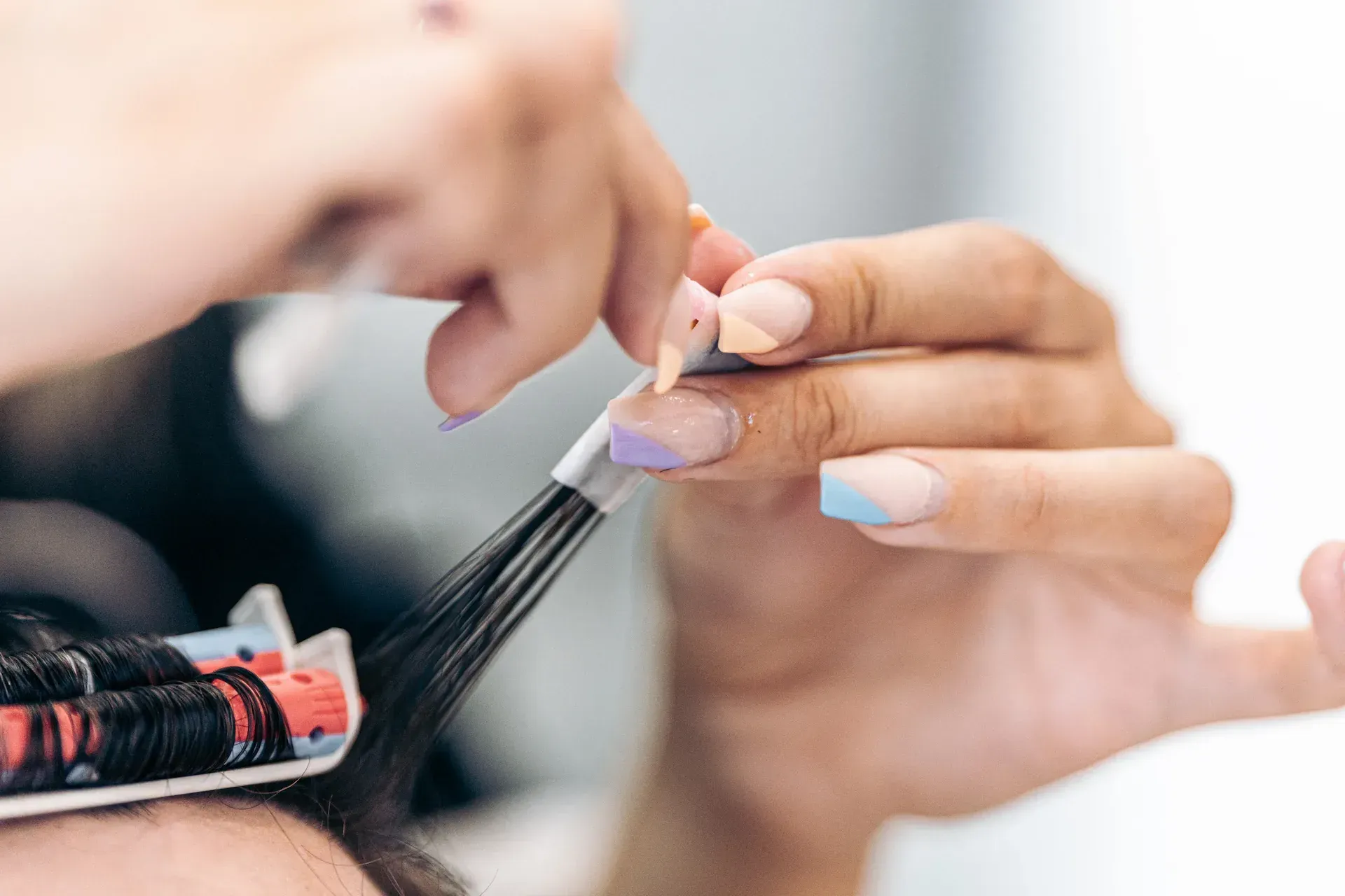 Una peluquera peina el cabello mojado en un salón. Hay otras personas al fondo.