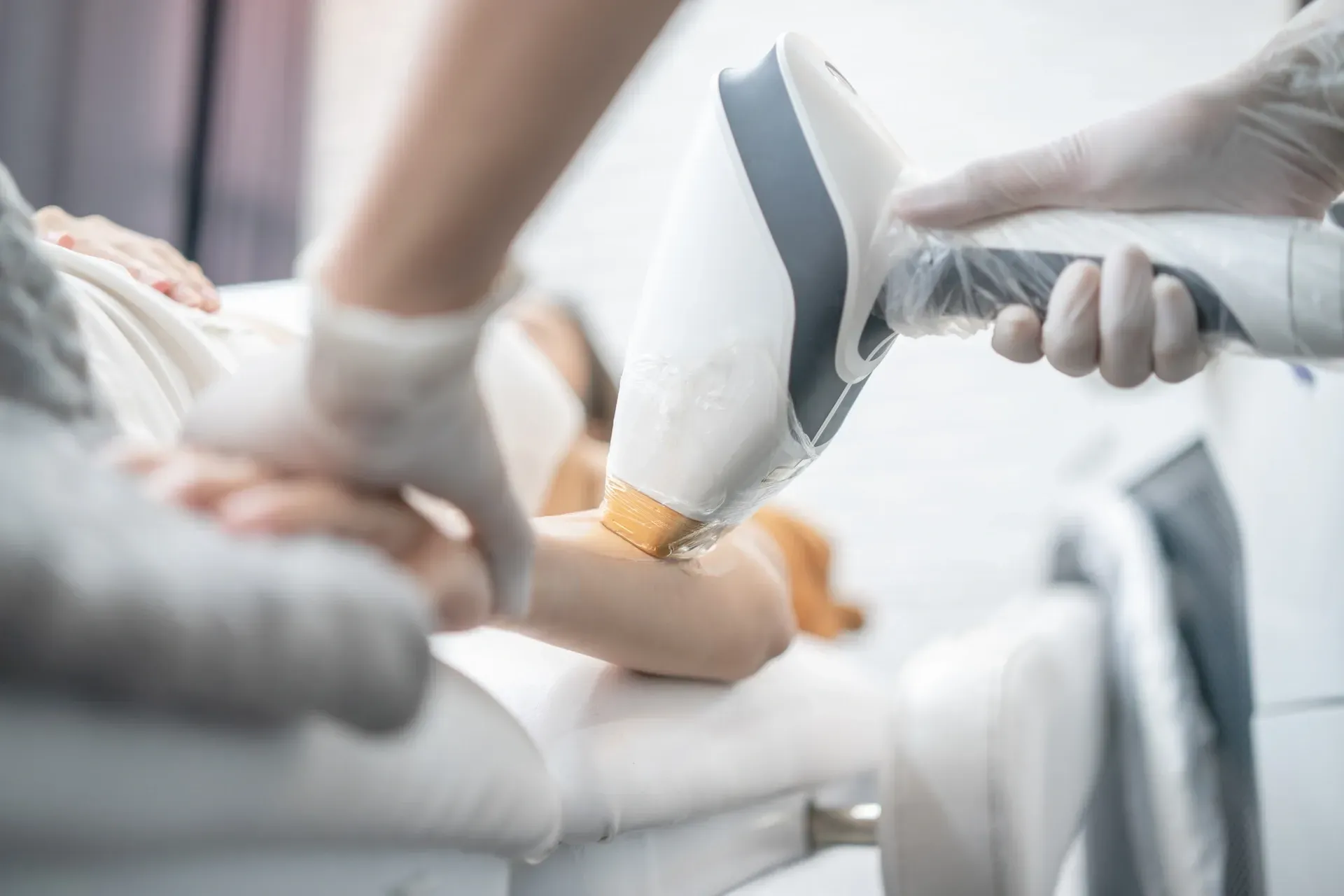 Una peluquera peina el cabello mojado en un salón. Hay otras personas al fondo.